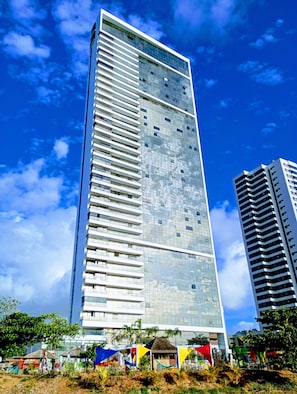 Un edificio alto y moderno con fachada de vidrio reflectante y varios balcones.