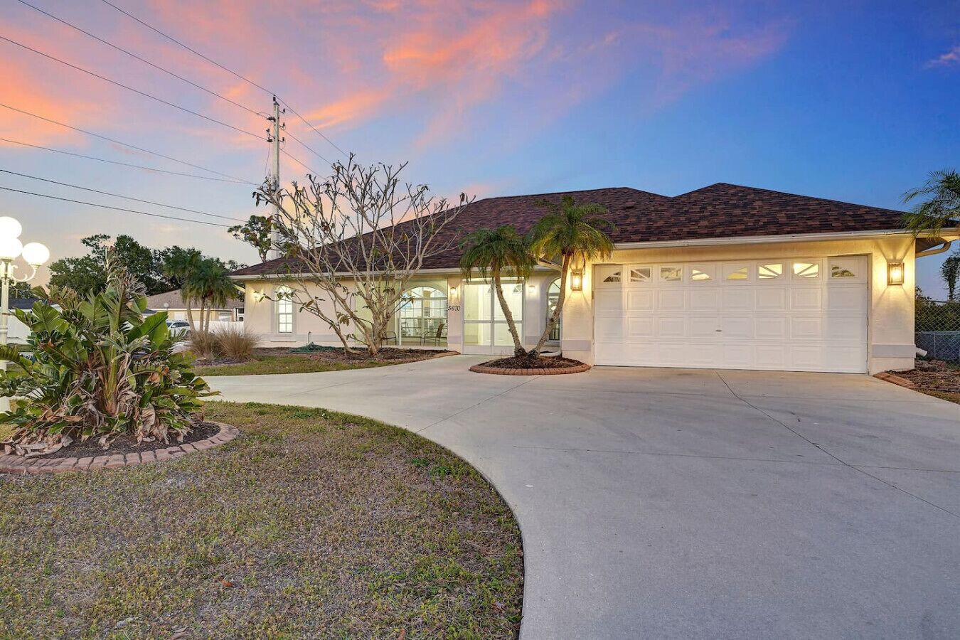 A residential house with a garage, a driveway, and a landscaped front yard.
