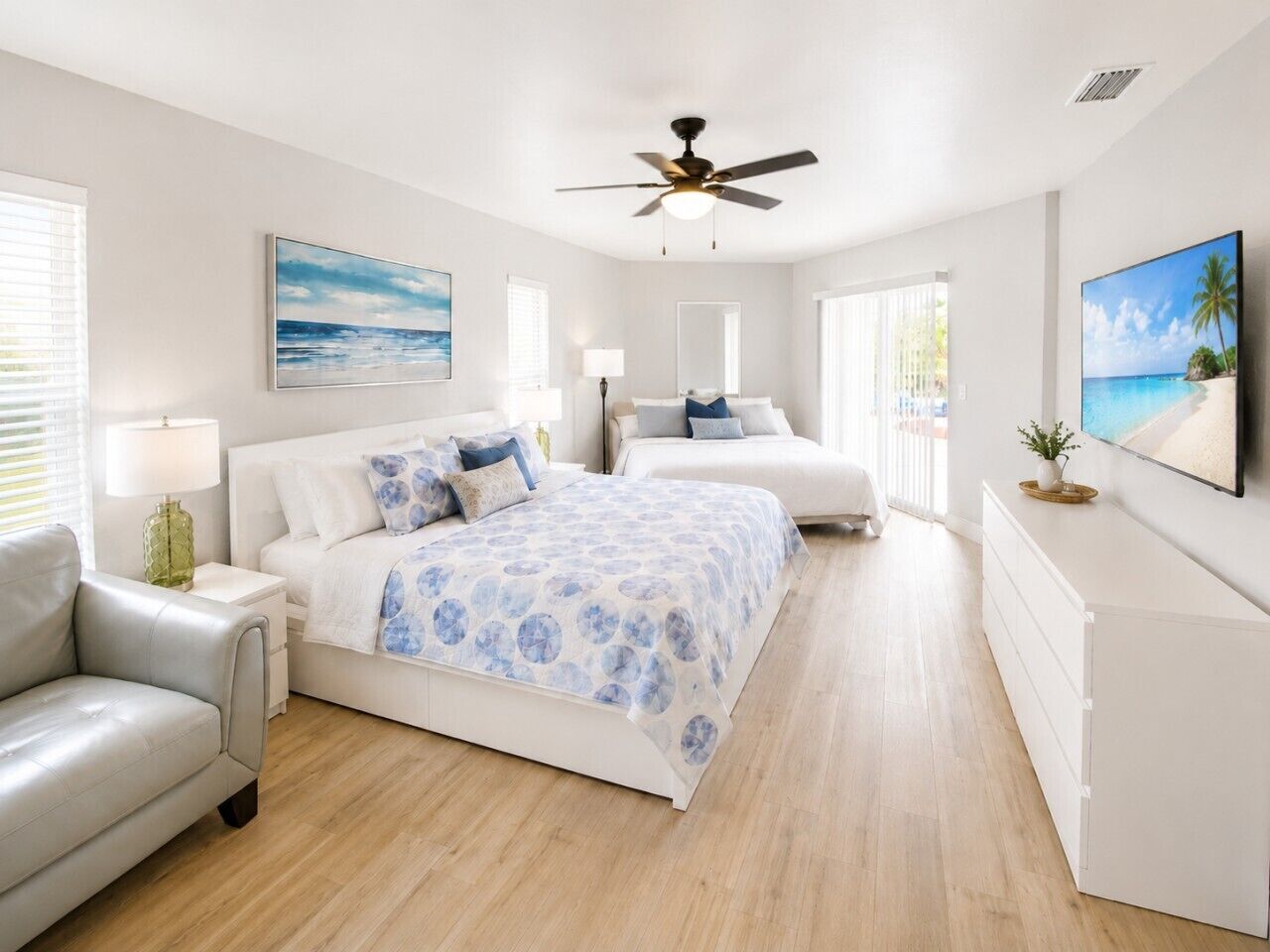 A modern bedroom with a large bed, a smaller bed, a sofa, and a TV.