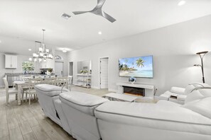 Un salon moderne avec un canapé blanc, une cheminée et un téléviseur fixé au mur.