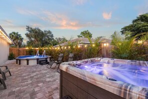 Un jardin avec un jacuzzi, une piscine et des chaises longues.