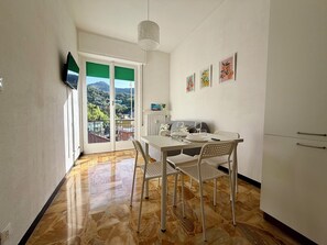 A dining area with a table, chairs, a hanging light fixture, and a view through a door. - Schiappacasse 11 - One Bedroom Apartment, Sleeps 3 (Rapallo)