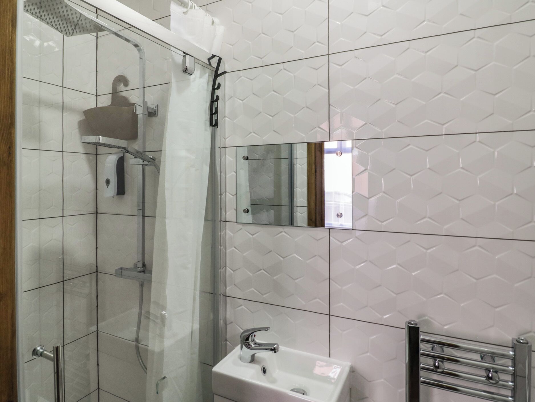 Een badkamer met een douchecabine van glas, een wit wastafelmeubel en een spiegel.