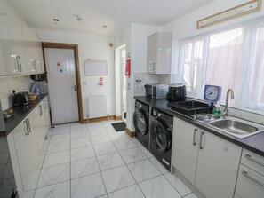 A modern kitchen with a built-in washing machine, a sink, and a window with curtains. - JMG House (West Bromwich)