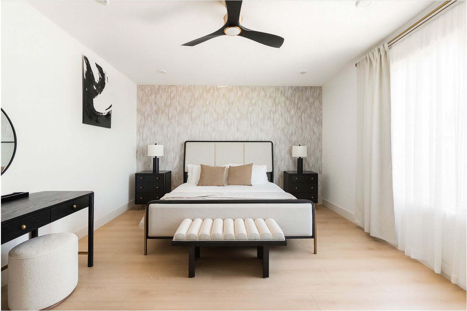 A bedroom with a bed, bedside tables, a desk, a chair, and a ceiling fan.