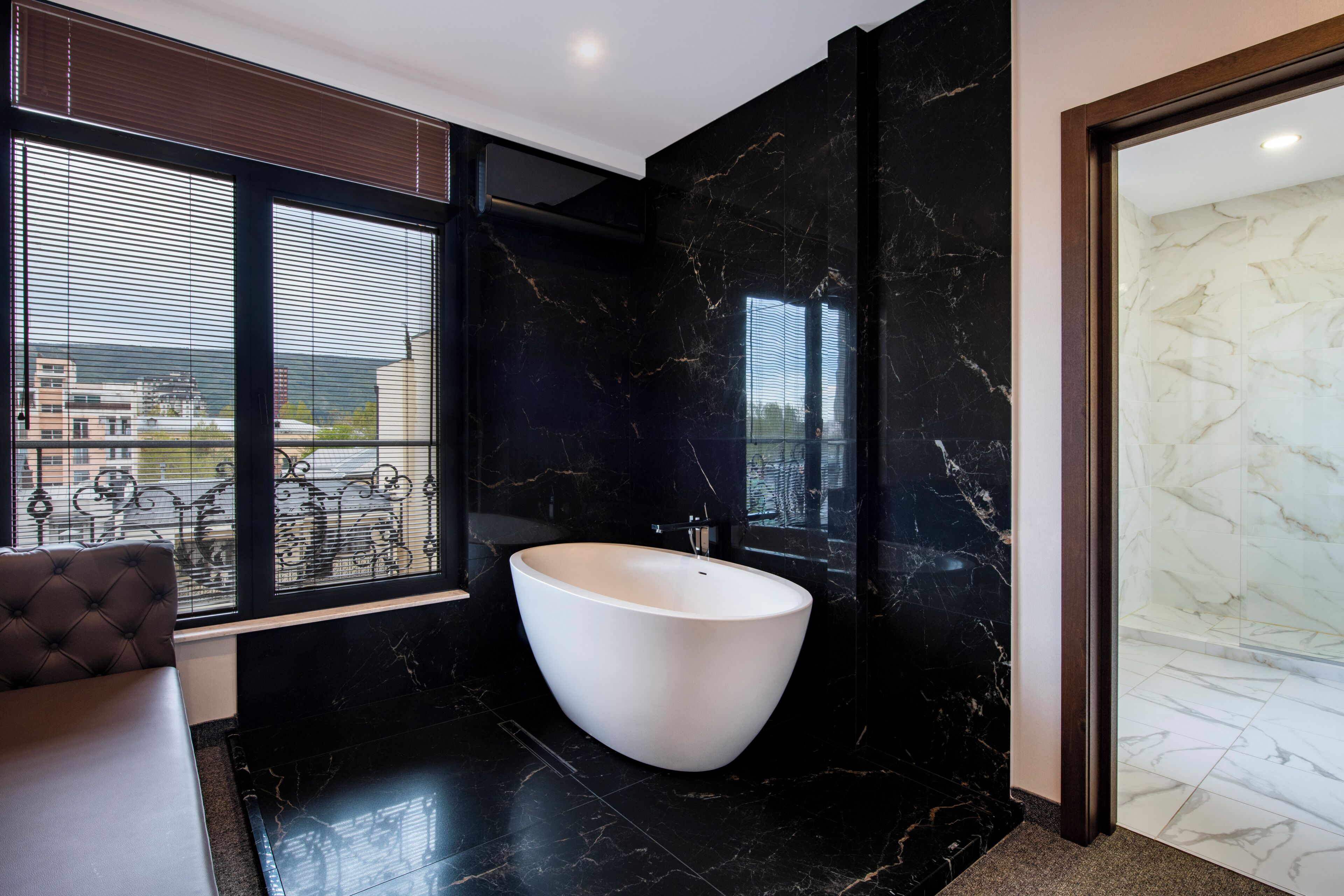 Un baño moderno con una bañera independiente, ventanas amplias y vistas a la ciudad.