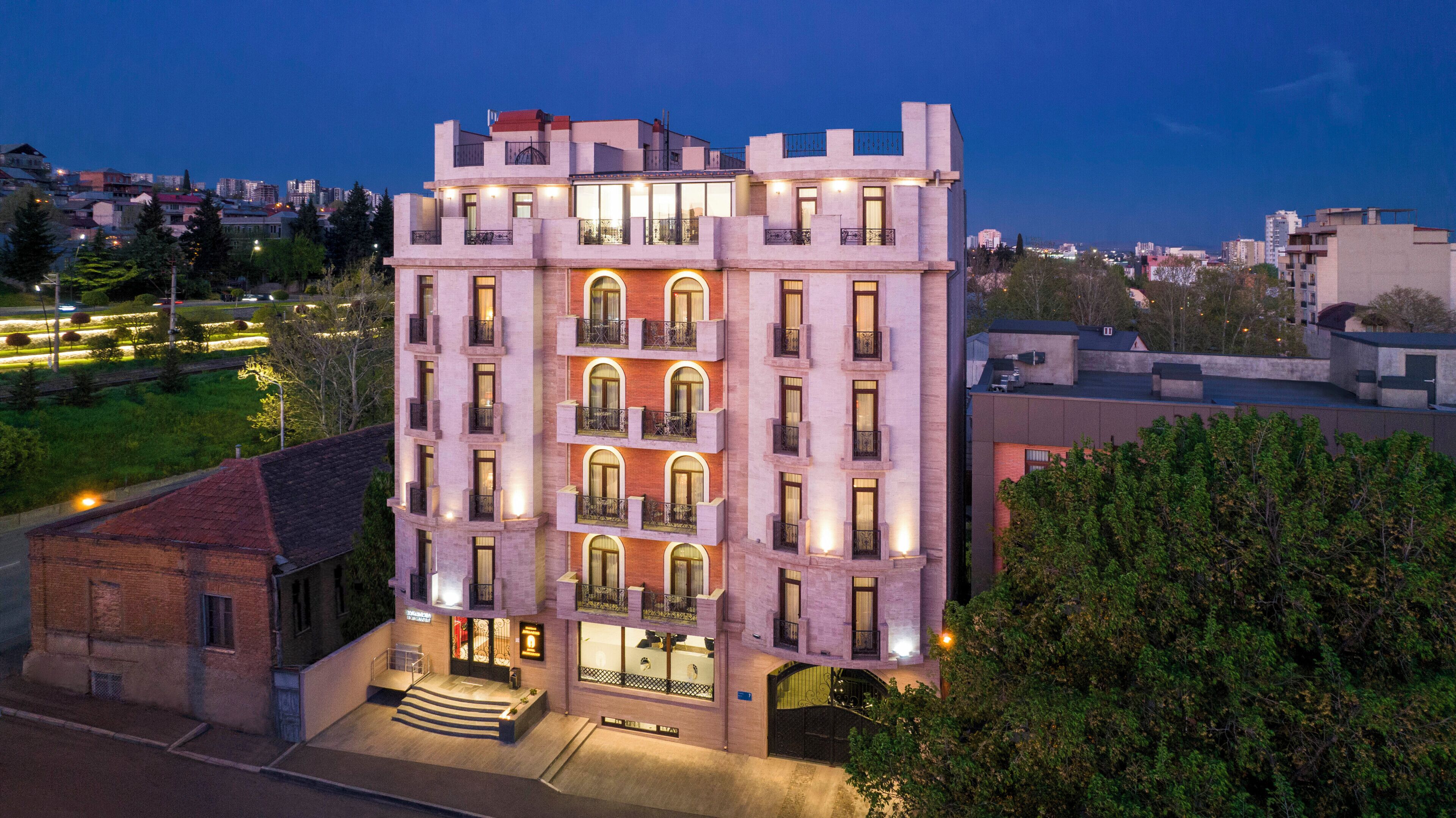 Un hotel de varios pisos con un patio central, balcones y vistas de la ciudad circundante.