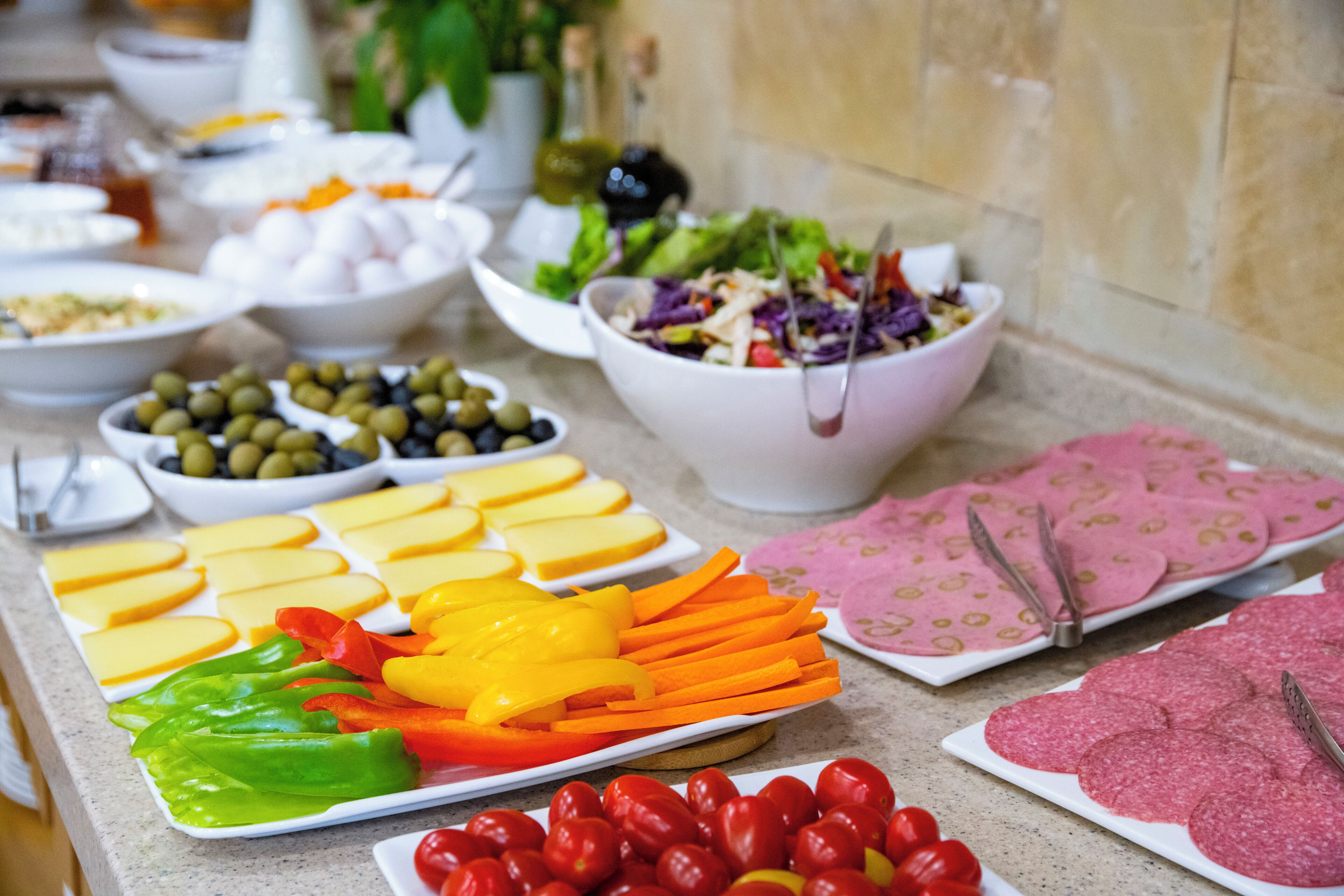 A buffet with various food items including cheese, vegetables, and meats.