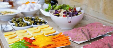 Un bufé con diversas opciones de comida, incluyendo queso, verduras y carnes.