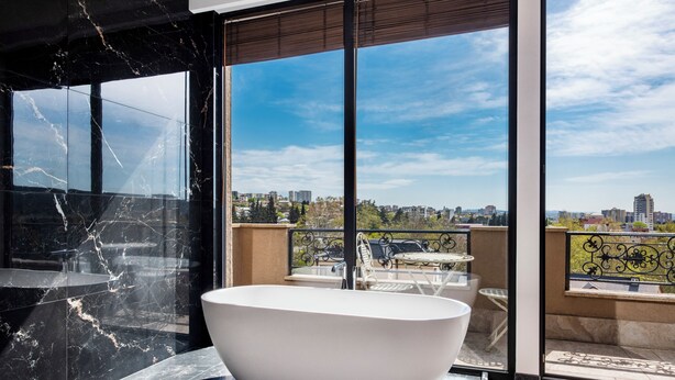 Une salle de bain moderne avec une baignoire sur pieds, de grandes fenêtres et une vue sur la ville.
