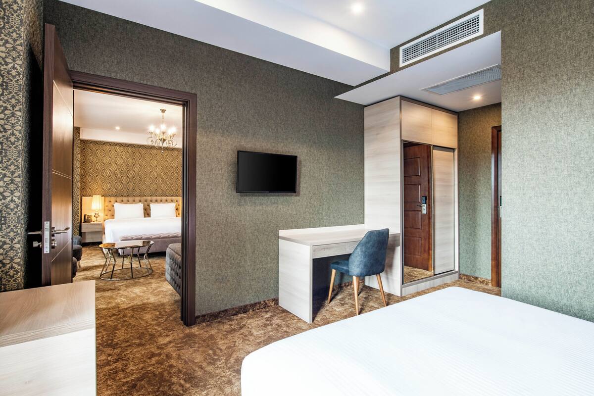 Une chambre d’hôtel comprenant un lit, un bureau, une chaise, une télévision et une salle de bain séparée.