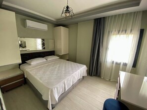 A hotel room with a bed, a desk, a chair, a mirror, and a window with curtains. - Easy Stay Mia Suites (Kuşadası)