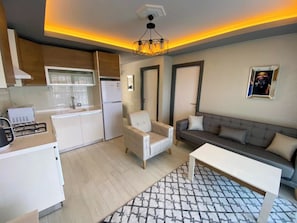 A modern living room with a sofa, armchair, and coffee table. - Easy Stay Mia Suites (Kuşadası)
