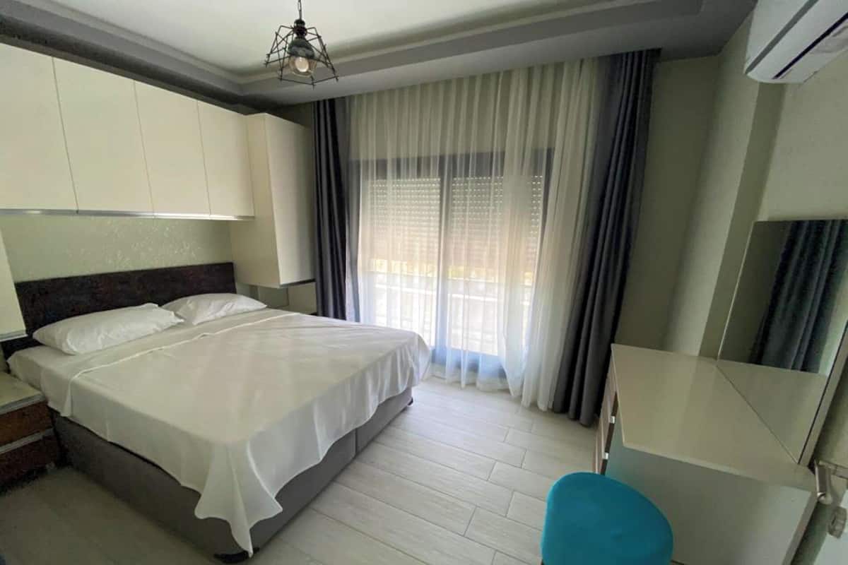 Une chambre d’hôtel avec un lit, un bureau, une chaise et une fenêtre avec des rideaux.