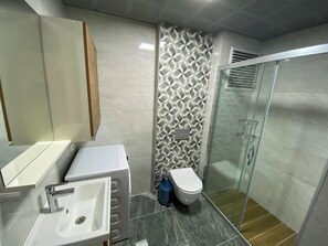A modern bathroom with a sink, toilet, and glass shower enclosure. - Easy Stay Mia Suites (Kuşadası)
