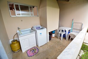 Un área de lavandería compacta con lavadora, secadora y cilindro de gas.