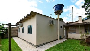 A small, single-story building with a flat roof, a water tank on the roof, and a paved patio area.