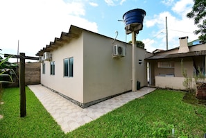 A small, single-story building with a flat roof, a water tank on the roof, and a paved patio area.
