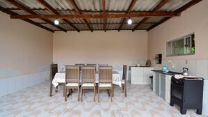 A kitchen with a tiled floor, a dining table with chairs, a sink, and a stove. - Casa Aconchegante na Gamboa - GAR003 (Garopaba)