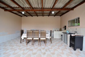 Uma cozinha com piso em azulejos, uma mesa de jantar com cadeiras, uma pia e um fogão.