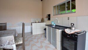 A compact kitchen with a dining table, a sink, a stove, and cabinets. - Casa Aconchegante na Gamboa - GAR003 (Garopaba)
