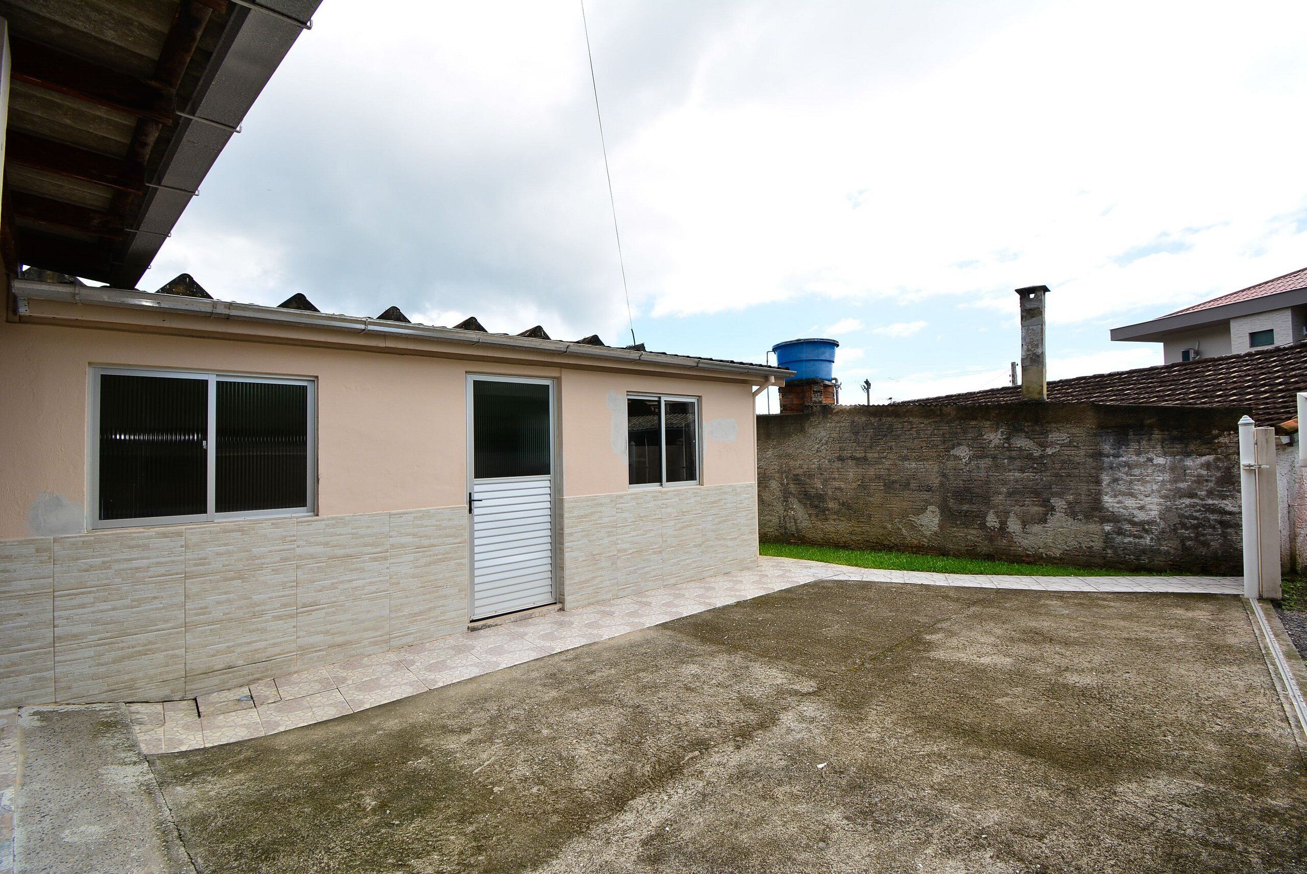 Um edifício residencial com telhado de telhas, um reservatório de água e um caminho de acesso de concreto.