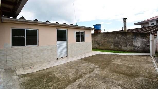 A residential building with a tiled roof, a water tank, and a concrete driveway. - Casa Aconchegante na Gamboa - GAR003 (Garopaba)
