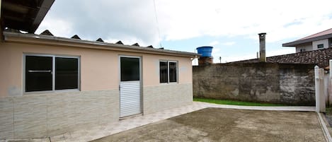 A residential building with a tiled roof, a water tank, and a concrete driveway.
