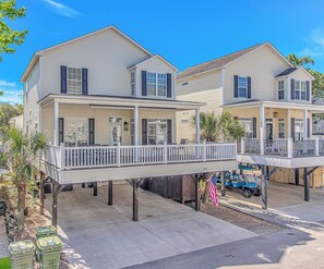 A two-story house with a balcony, a garage, and a small porch area. - Gorgeous 5-bdrm site 5713 Ocean Lakes golf cart interior elevator (Myrtle Beach)
