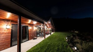 Een modern gebouw met een overdekt terras, grote ramen en buiten zitplaatsen.