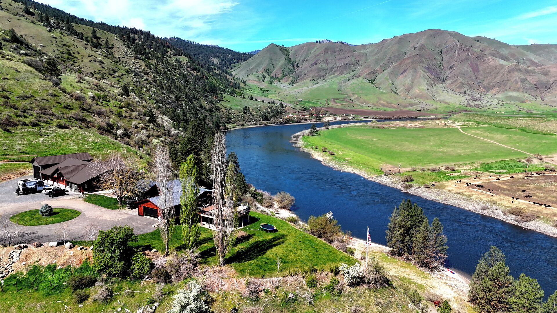 A riverside property with a house, a driveway, and a fenced yard.