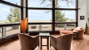 Une pièce dotée de grandes fenêtres, de fauteuils en cuir, d’une petite table et offrant une vue sur la plage.