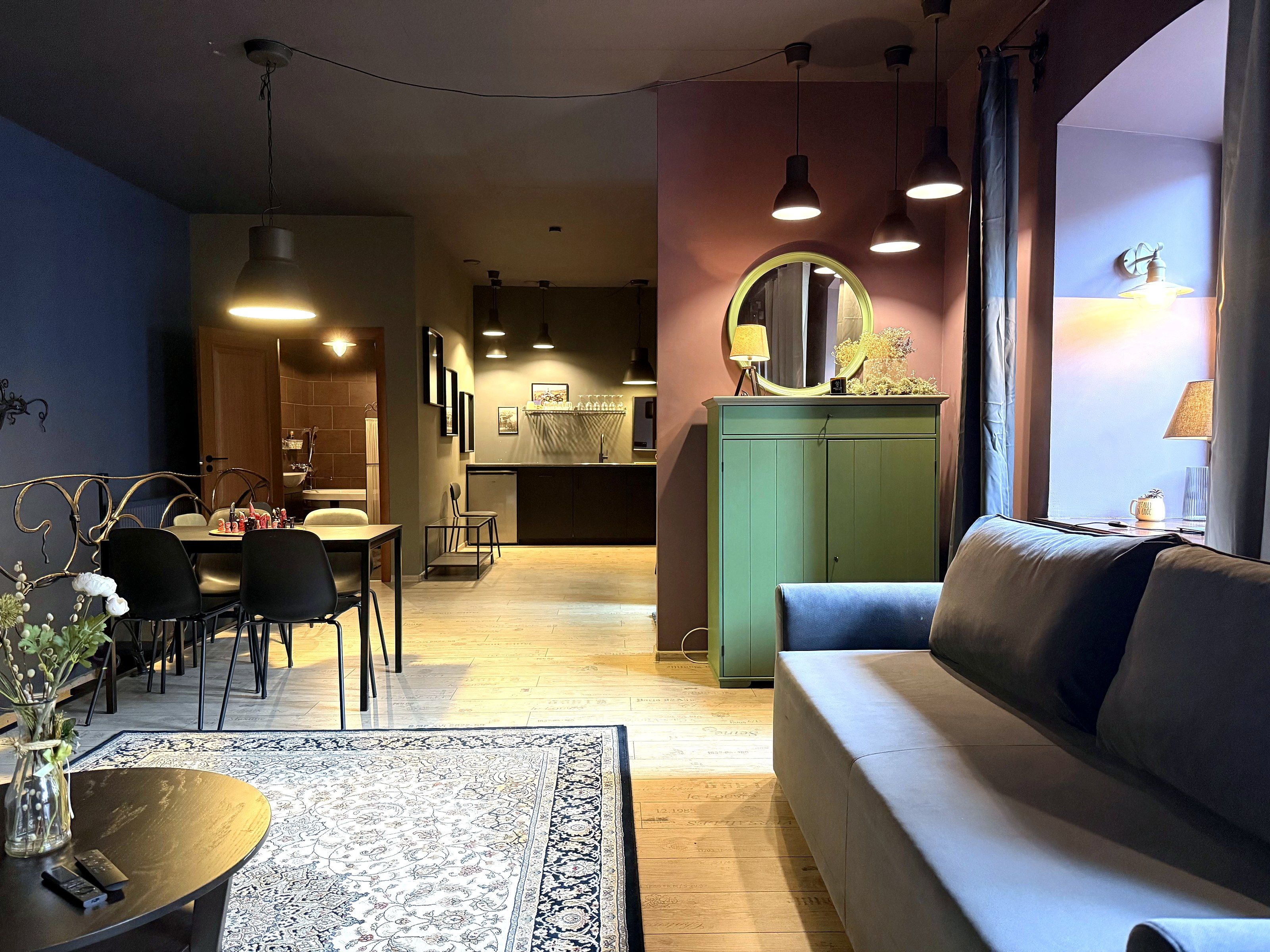 A modern living room with a sofa, dining area, and kitchen in the background.