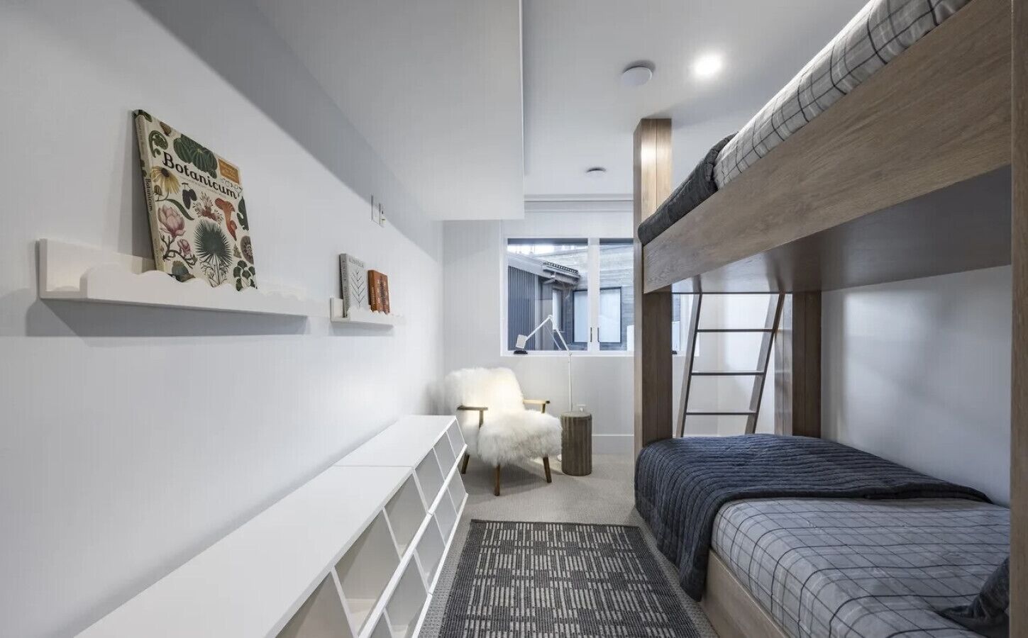 Une chambre moderne avec un lit superposé, une chaise blanche, un bureau et une fenêtre donnant sur un beau paysage.