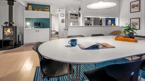Een moderne keuken met witte kasten, een centraal eiland en een eethoek met een ronde tafel en stoelen.