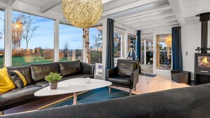 Een moderne woonkamer met een leren bank, een salontafel en een grote bolvormige lamp.