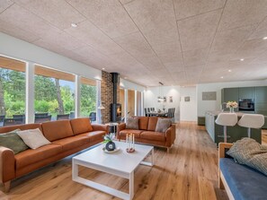 Ein großzügiger Wohnbereich mit Kamin, zwei Sofas, einem Couchtisch und einem Essbereich mit Stühlen.