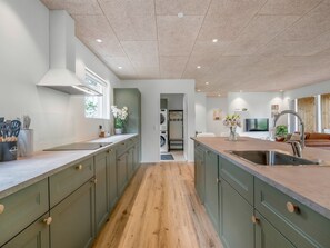 Eine moderne Küche mit einer zentralen Kochinsel, Holzboden und grünen Küchenschränken.