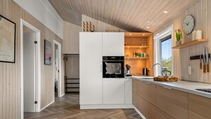 Una cocina moderna con armarios de madera, horno empotrado y ventana con vistas al exterior.