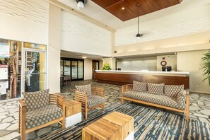 A hotel lobby with a reception desk, seating area, and a patterned floor. - 5 Min to Beach | 1BR Lanai, Rooftop Pool+Hot Tub (Honolulu)