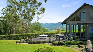 A modern house with a patio, outdoor seating, and a scenic view of hills. - Newhaven - Kangaroo Valley (Upper Kangaroo River)
