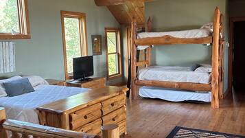 A cabin interior with a bunk bed, wooden furniture, a ceiling fan, and a television.