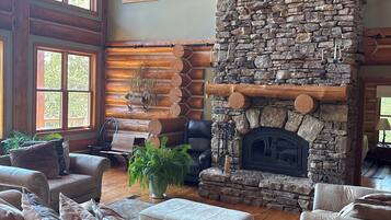A cozy living room with a stone fireplace, leather sofas, and a wooden ceiling.