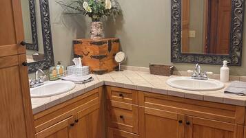 A bathroom with wooden cabinets, a sink, a mirror, and a vase with flowers.