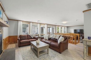 A living room with a brown leather sofa set, a coffee table, and a TV.