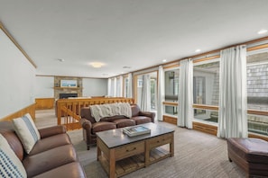 A spacious living room with a fireplace, a dining area, and large windows.