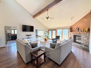 A spacious living area with a fireplace, a dining area, and a kitchen. - Cozy Cove Escape – Lakefront (Linn Creek)