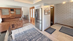 Una cocina moderna con armarios de madera, un refrigerador de acero inoxidable y una alfombra estampada.