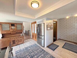 A modern kitchen with wooden cabinets, a stainless steel refrigerator, and a patterned rug. - Cozy Cove Escape – Lakefront (Linn Creek)