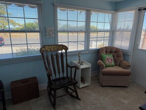 A room with a rocking chair, a cushioned chair, a small white table, and a wicker basket. - Beautiful 3-bedroom bay side house with AC in charming Lavallette (Lavallette)
